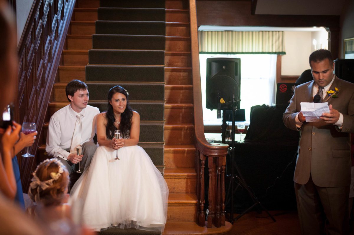 couple sitting on stairs while family member gives toast