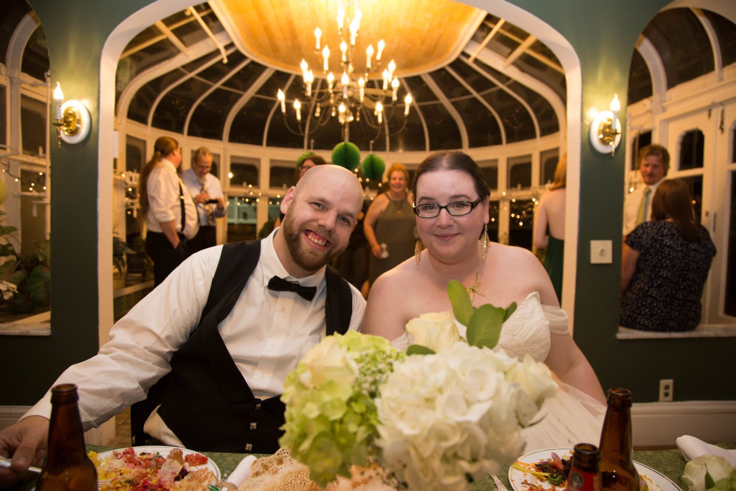 shaina and zach at head table with conservatory in the background