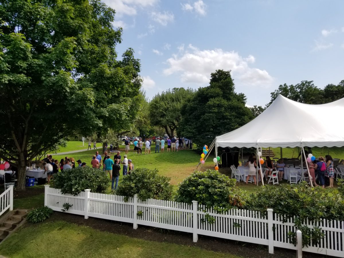 tent on back lawn with people playing lawn games