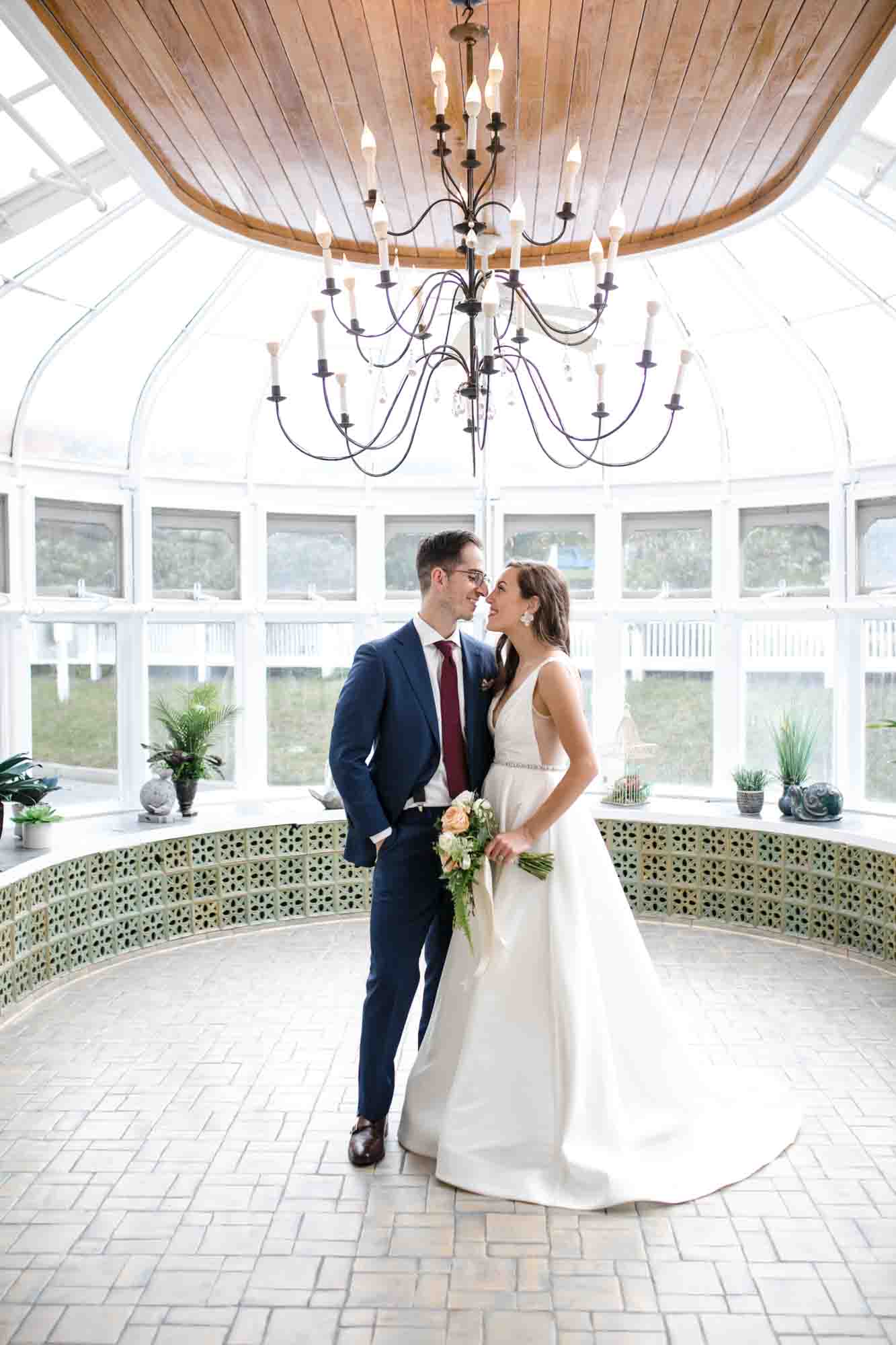 bride and groom standing close in glass conservatory